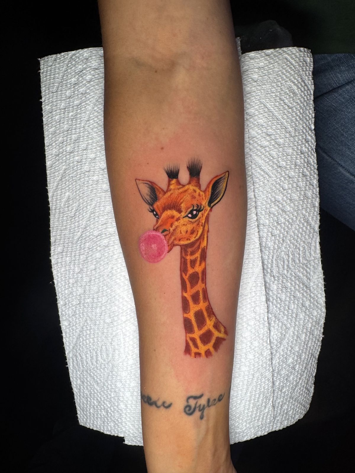 Giraffe blowing a pink bubble gum bubble, calf tattoo