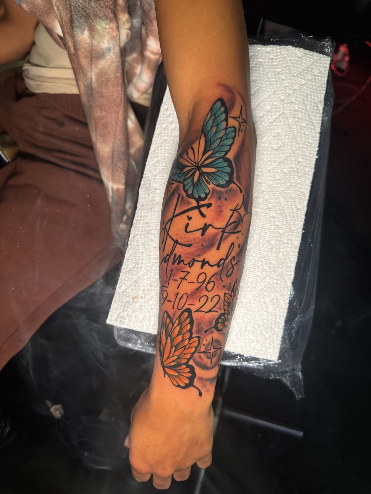 Butterflies with script names and dates, forearm tattoo