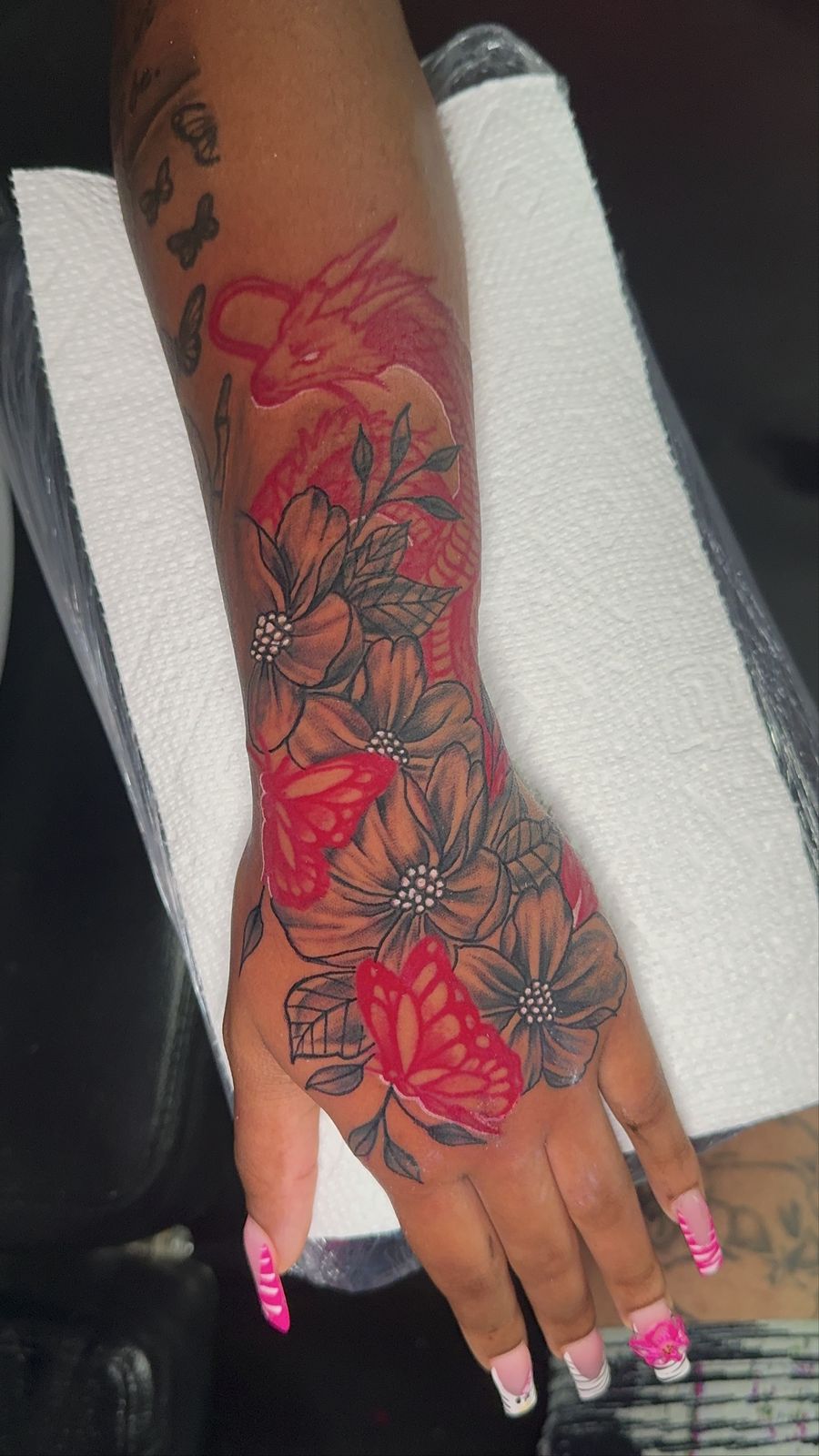 Red dragon with florals and butterflies, hand and forearm